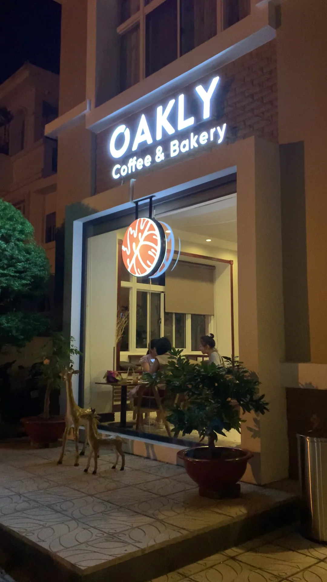 Mặt tiền OAKLY Coffee & Bakery với ánh đèn ấm vào buổi tối